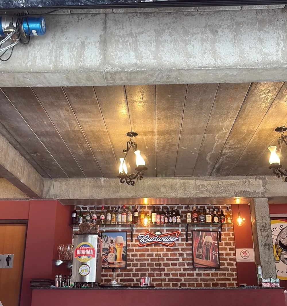 Balcão do bar com parede de tijolos, garrafas e luminárias