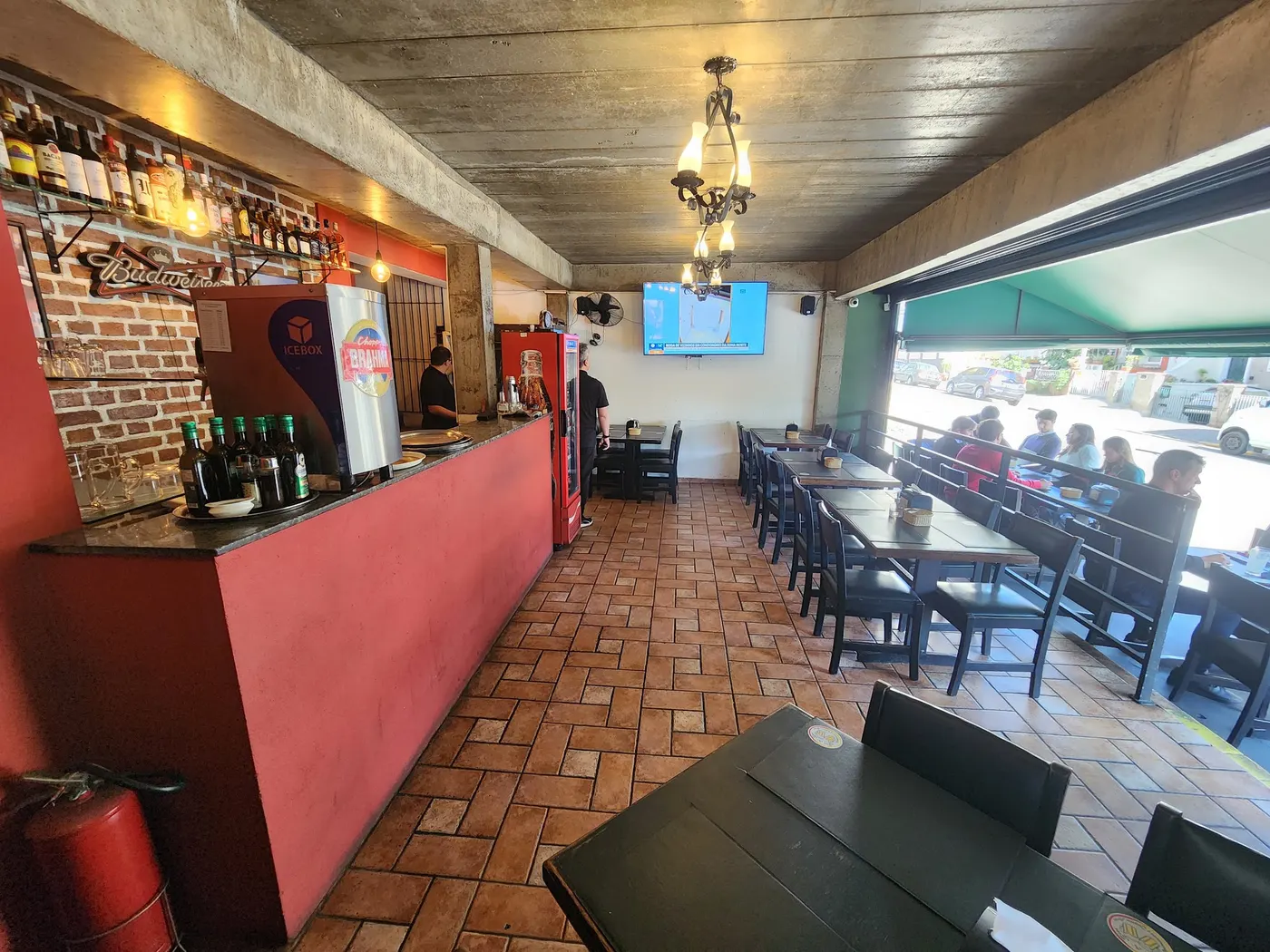 Salão do Bier & Bier com piso de cerâmica, balcão vermelho e lustre